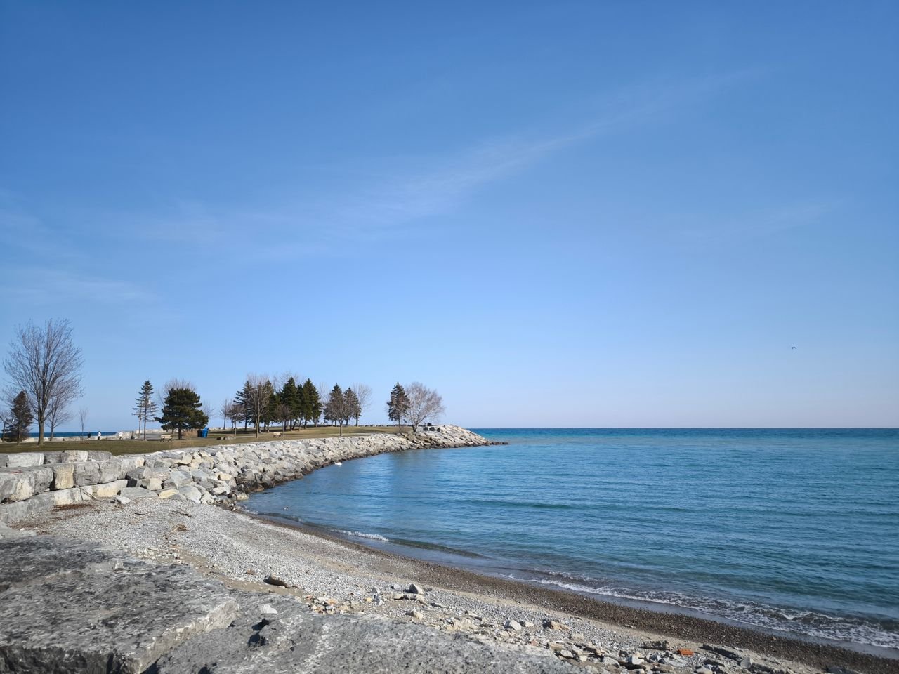 service-05 Tranquil landscape of Lake Ontario with blue skies and rocky beach in Toronto, Canada.